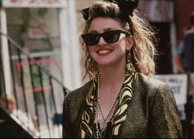 6 tendências de agora que Madonna adiantou décadas atrás Madonna usa óculos wayfarer da ray-ban e laço na cabeça no filme busca-se susan desesperadamente