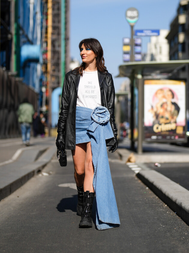 As principais tendências de minissaia da temporada Tendências de minissaia: saia jeans curta traz aplicação de flor e tecido longo na lateral. A saia é complementada com camiseta branca, jaqueta de couro e ankle boot preta