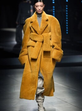 Os principais casacos e jaquetas do próximo inverno Modelo desfila com casaco longo em cor mostarda e textura peludinha no inverno 2023 da Andreamo