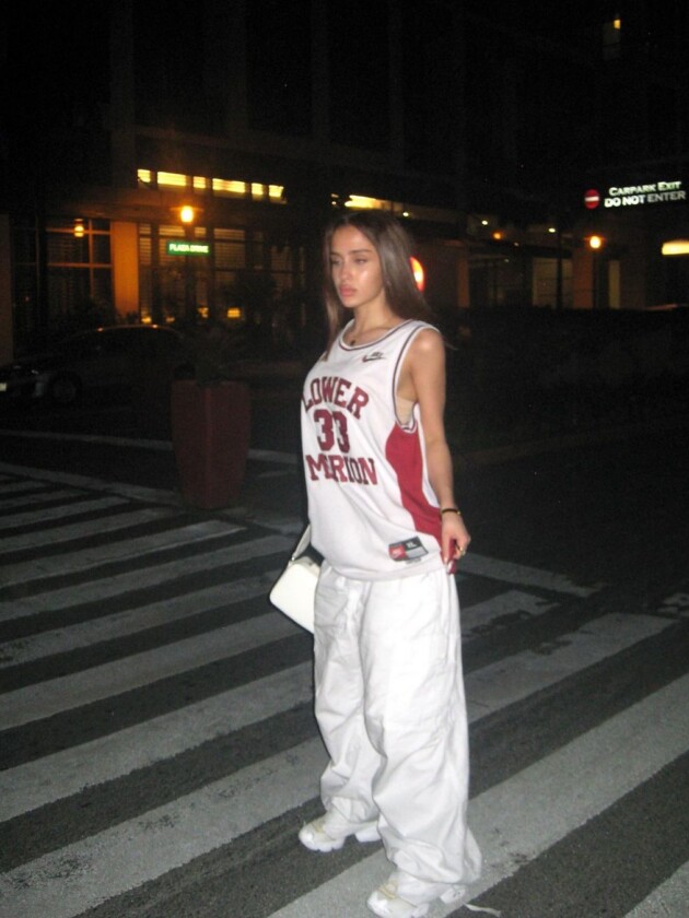 Como usar camisa de time: 5 dicas para incorporar a tendência esportiva Camisa de basquete é usada com calça parachute branca em look esportivo