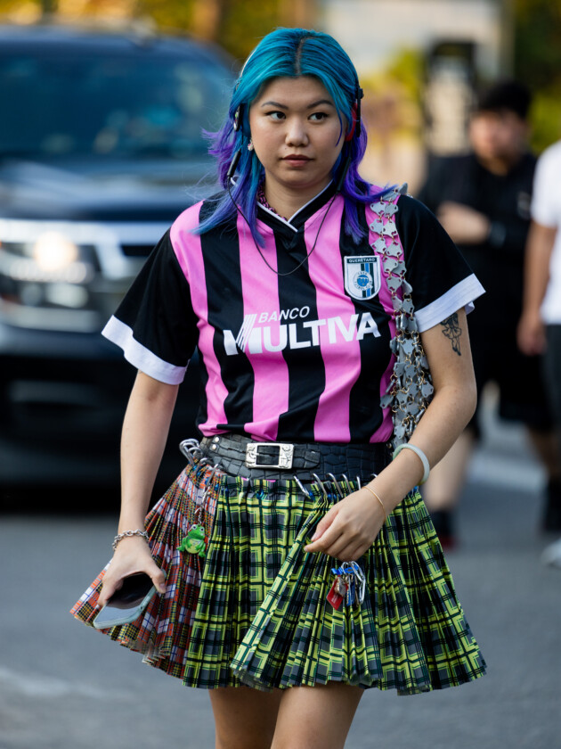 Como usar camisa de time: 5 dicas para incorporar a tendência esportiva Mulher usa camisa de time de futebol listrada com saia xadrez. A blusa de uniforme esportivo é tendência