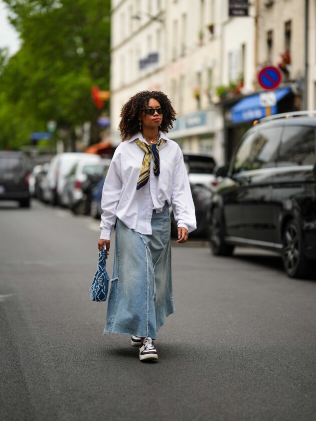 5 tendências de jeans para além do básico saia jeans comprida é usada com camisa branca, tênis e lenço no pescoço