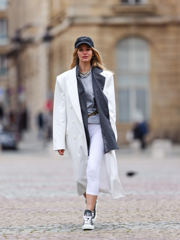 O retorno da calça capri: 5 maneiras de usar Legging capri branca é usada em look esportivo com boné, tênis, blazer cinza e casaco comprido branco