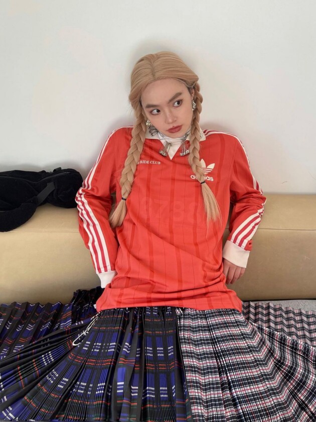 Como usar camisa de time: 5 dicas para incorporar a tendência esportiva Camisa esportiva de mangas longas vermelha é usada com saia xadrez