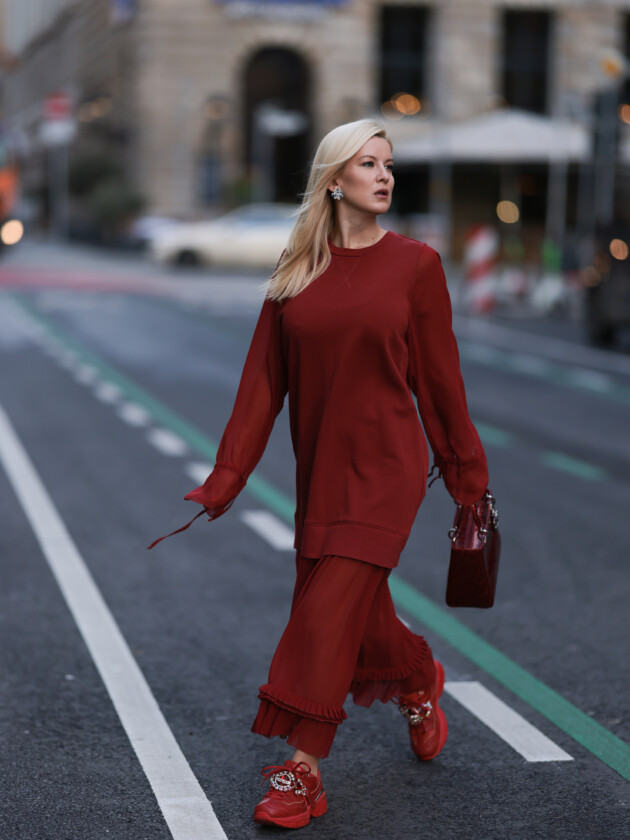 BERLIN, GERMANY - JANUARY 17: Palina Kozyrava seen wearing Maison Margiela Bordeaux long dress, Lady Dior small bag, Natkina silver jewelry, Skechers matching sneaker and Maurice Lacroix white watch before the show during the Berlin Fashion Week AW23 on January 17, 2023 in Berlin, Germany. (Photo by Jeremy Moeller/Getty Images) A tendência dos conjuntos femininos: Mulher usa conjunto vinho de blusa de mangas longas e saia comprida que se assemelha a um vestido