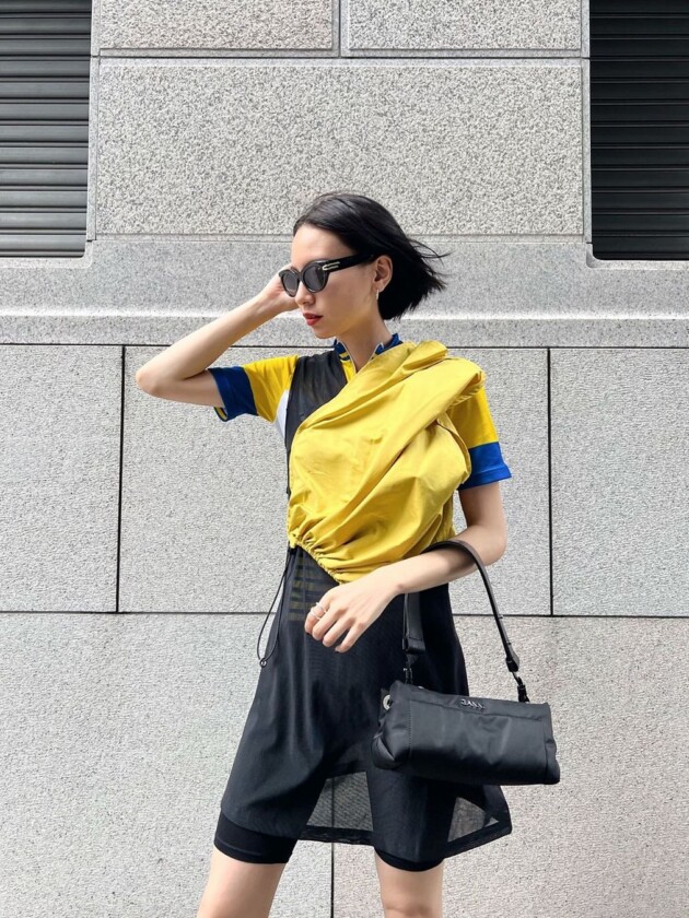 Como usar camisa de time: 5 dicas para incorporar a tendência esportiva Camisa de time colorida é usada por debaixo de vestido preto e amarelo