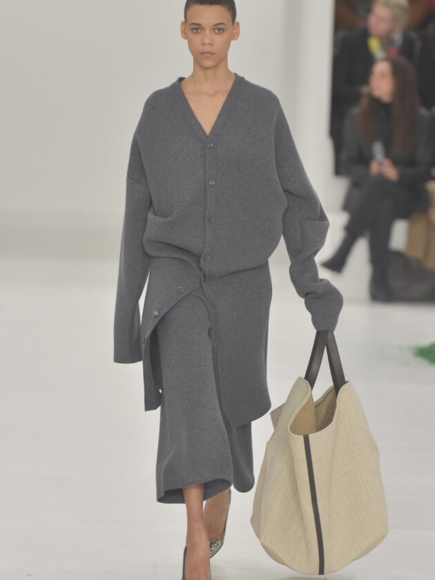 O boom dos conjuntos na moda: 10 estilos para ficar de olho A tendência dos conjuntos femininos: Modelo da loewe desfile com conjunto cinza de cardigã e saia de malha no inverno 2023