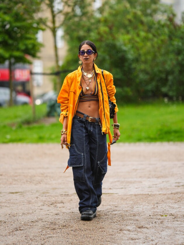 5 tendências de jeans para além do básico Jeans cargo é usado com blusa amarela aberta e top de crochê