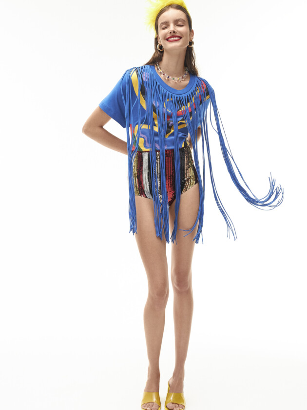 Vem ver os abadás do camarote da moda! mulher com camiseta azul com franjas compridas, do camarote Soma, e hotpants com paetê