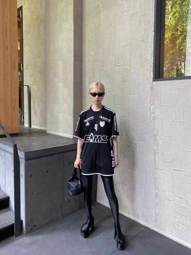 Como usar camisa de time: 5 dicas para incorporar a tendência esportiva Camisa de time oversized e comprida é complementada com legging texturizada e bota pesada, ambas pretas