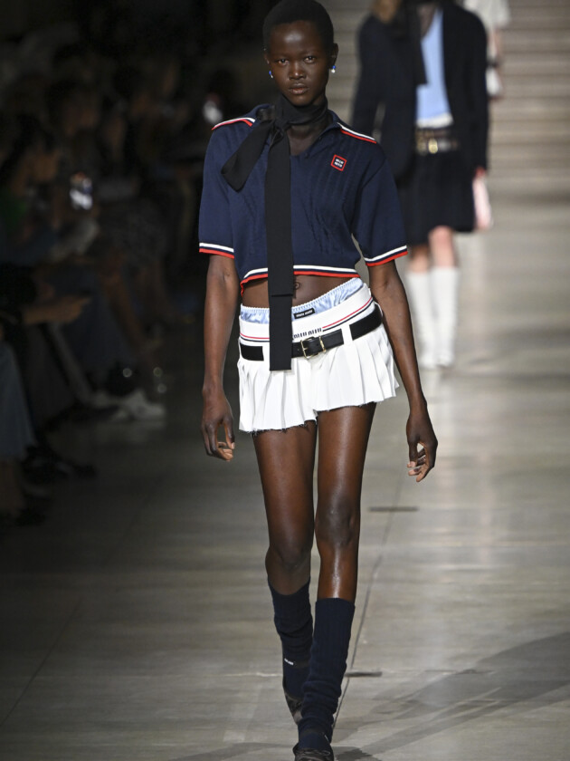 Tendências de minissaia: modelo desfila com saia curta branca com pregas, estilo tênis, na passarela de inverno 2022 da Miu Miu