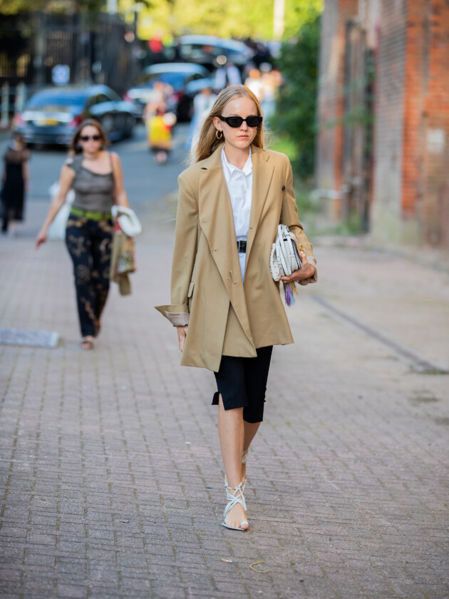 O retorno da calça capri: 5 maneiras de usar Calça capri preta é usada com camisa branca social e blazer bege oversized