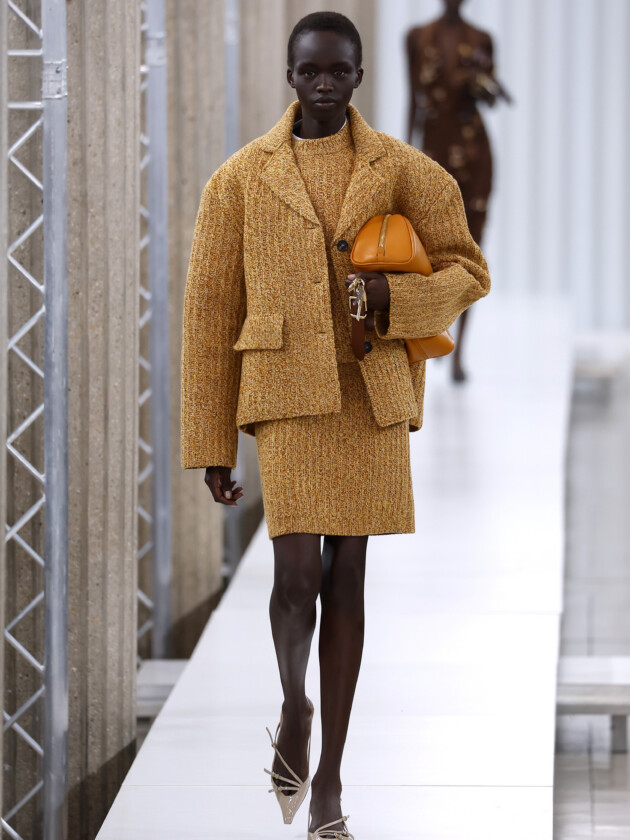 O boom dos conjuntos na moda: 10 estilos para ficar de olho A tendência dos conjuntos femininos: Modelo desfile com conjunto completo de saia, blusa e jaqueta em tecido mostarda