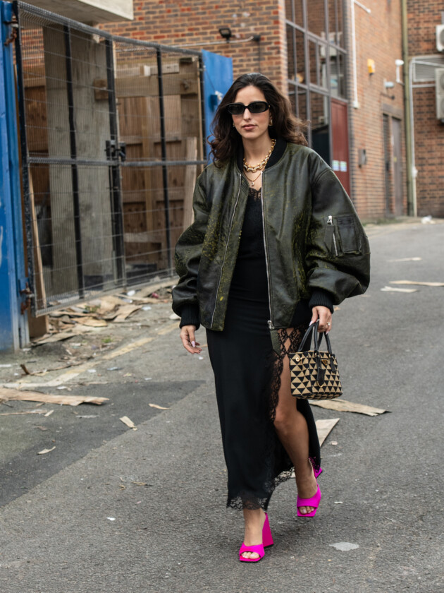 7 ideias para atualizar o slip dress neste inverno Slip dress preto acetinado é combinado à jaqueta bomber esverdeada e sandália pink