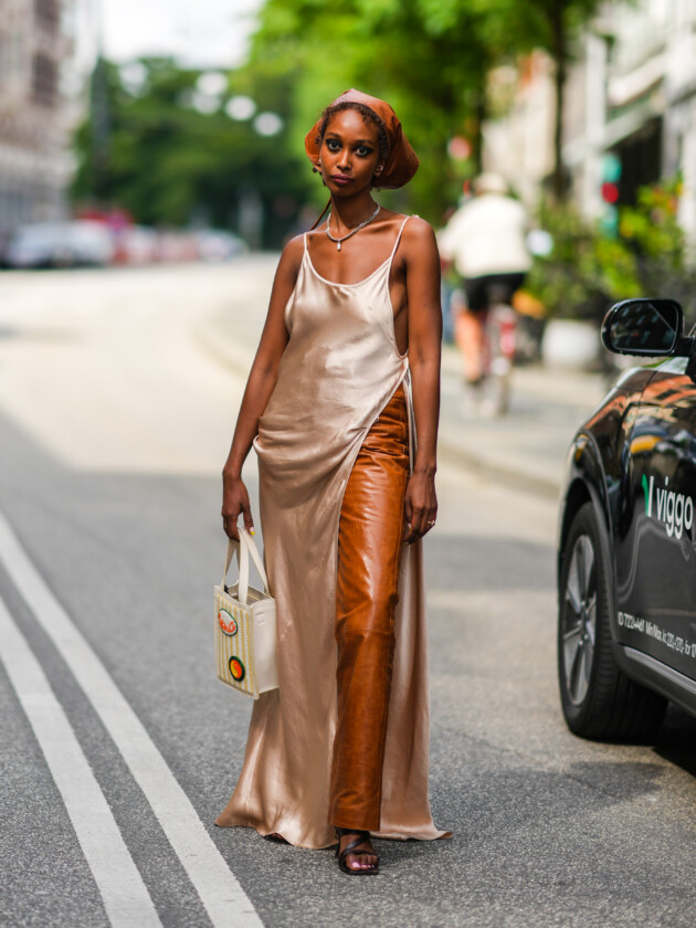 7 ideias para atualizar o slip dress neste inverno Sip dress acetinado na cor champanhe é usado com calça de couro caramelo. O vestido acaba ganhando efeito de blusa
